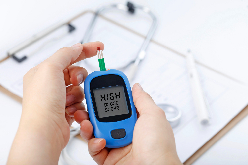 hand-holding-blood-glucose-meter-measuring-blood-sugar-background-is-stethoscope-chart-file (1)