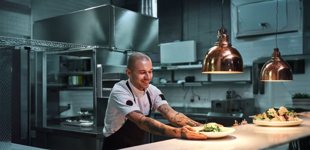 Ready,To,Serve.,Young,Smiling,Chef,With,Tattoos,On,His