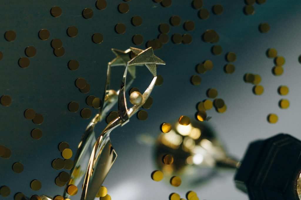 A gold trophy against a dark background surrounded by gold confetti.